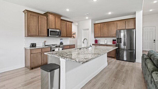 Una cocina moderna con armarios de madera, electrodomésticos de acero inoxidable y una isla de granito.