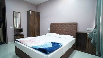 A bedroom with a bed, a wardrobe, a mirror, and a bedside table.