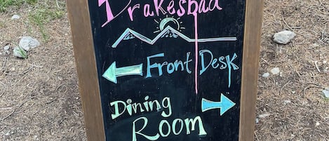 Un cartel de pizarra con indicaciones hacia la Recepción y el Salón de Comidas en Drakesbad.
