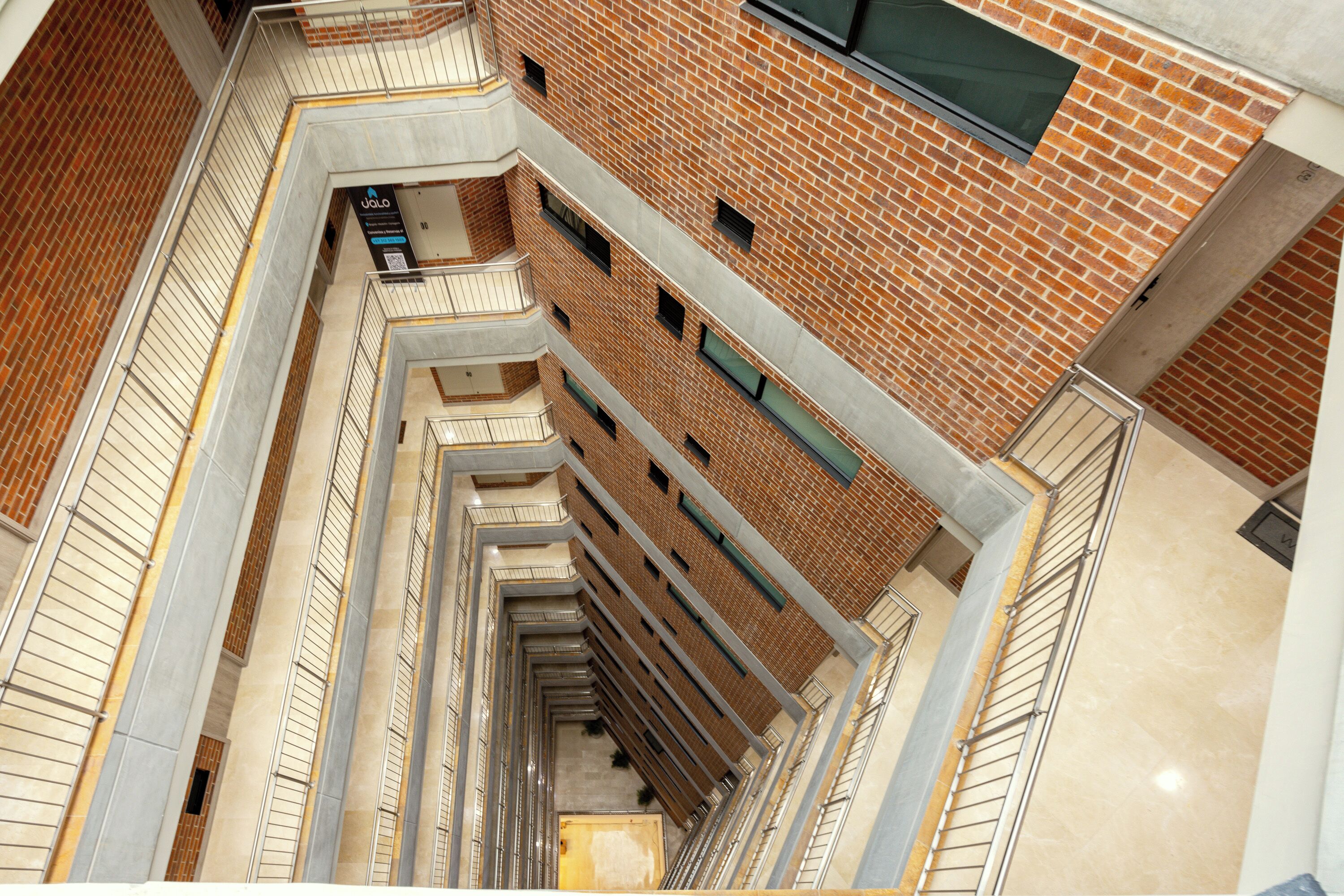 A multi-level interior with brick walls, metal railings, and a series of windows.