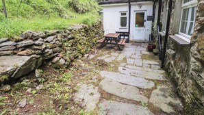 A stone-paved pathway leading to a white building with a door marked "Toilet." - Tryfan Cottage (Caernarfon)