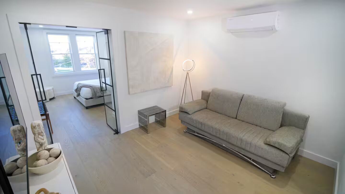 Un salon moderne avec un canapé, une lampe sur pied et une grande fenêtre.