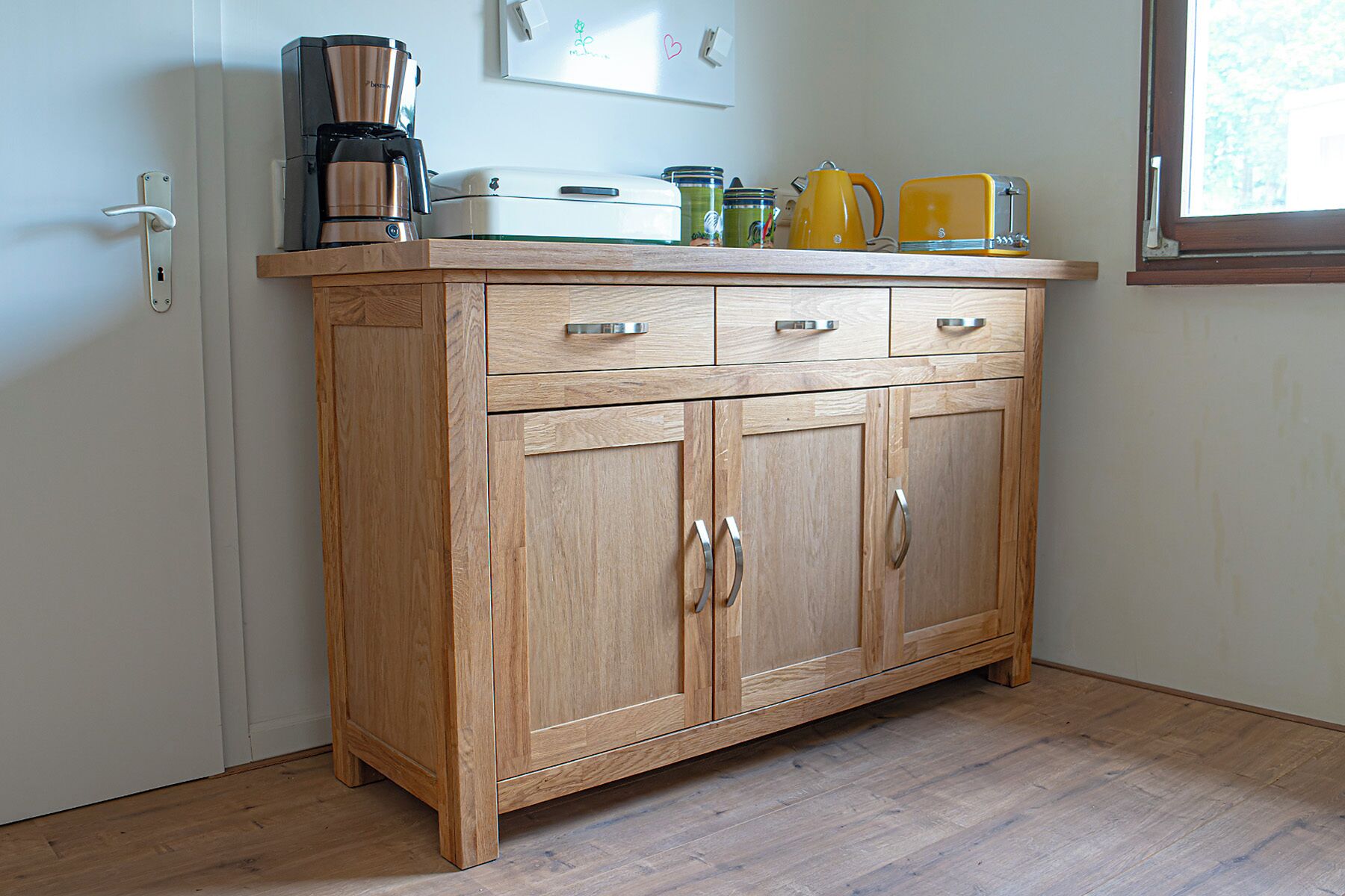Una cocina de madera con cafetera, tostadora y hervidor sobre la encimera.