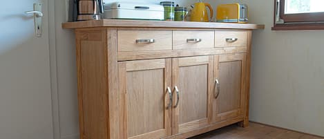 Una cocina de madera con cafetera, tostadora y hervidor sobre la encimera.