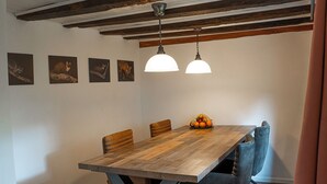 Un coin repas avec une table en bois, quatre chaises et deux lampes suspendues.