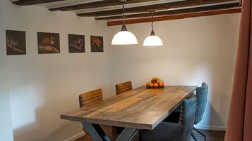 Un coin repas avec une table en bois, quatre chaises et deux lampes suspendues.