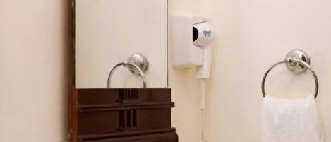 A bathroom with a sink, mirror, towel rack, and a hairdryer.