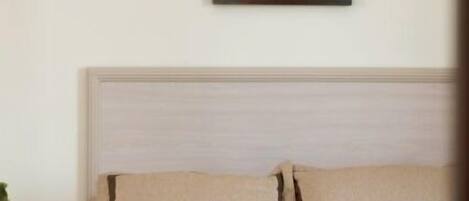 A bedroom with a bed, pillows, and a painting of a seashell on the wall.