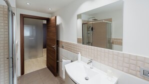 A modern bathroom with a large mirror, a white sink, and a shower area. - APARTMENT 1 (Misterbianco)
