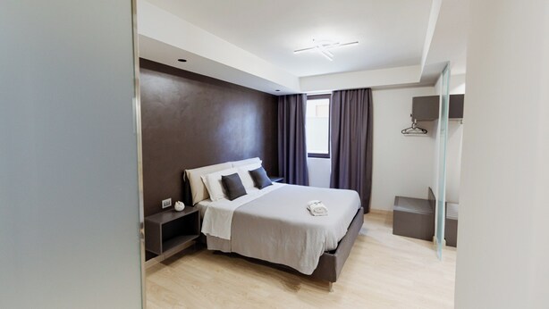 A modern bedroom with a large bed, a bedside table, a wardrobe, and a window with curtains. - APARTMENT 1 (Misterbianco)