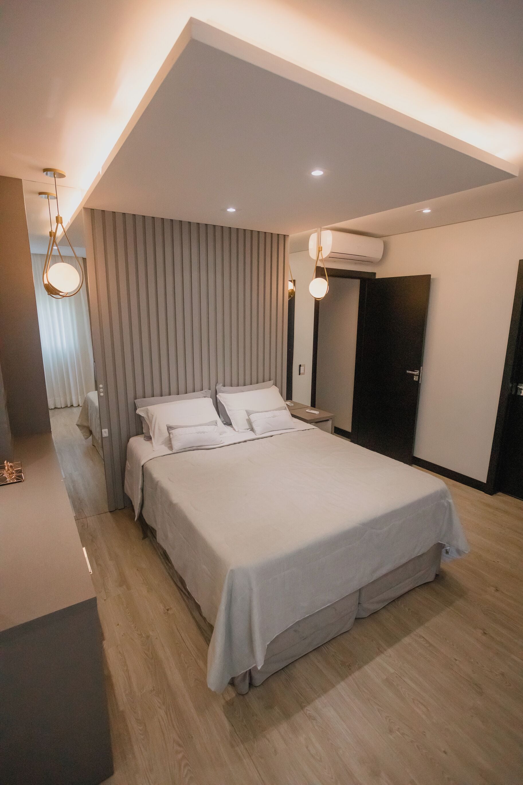 Un dormitorio moderno con una cama grande, una mesita de noche, un armario y una lámpara en el techo.