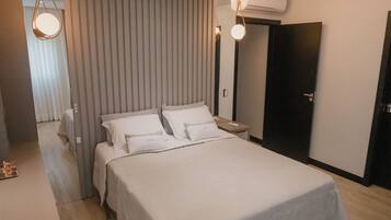 A modern bedroom with a large bed, a bedside table, a wardrobe, and a ceiling light fixture.