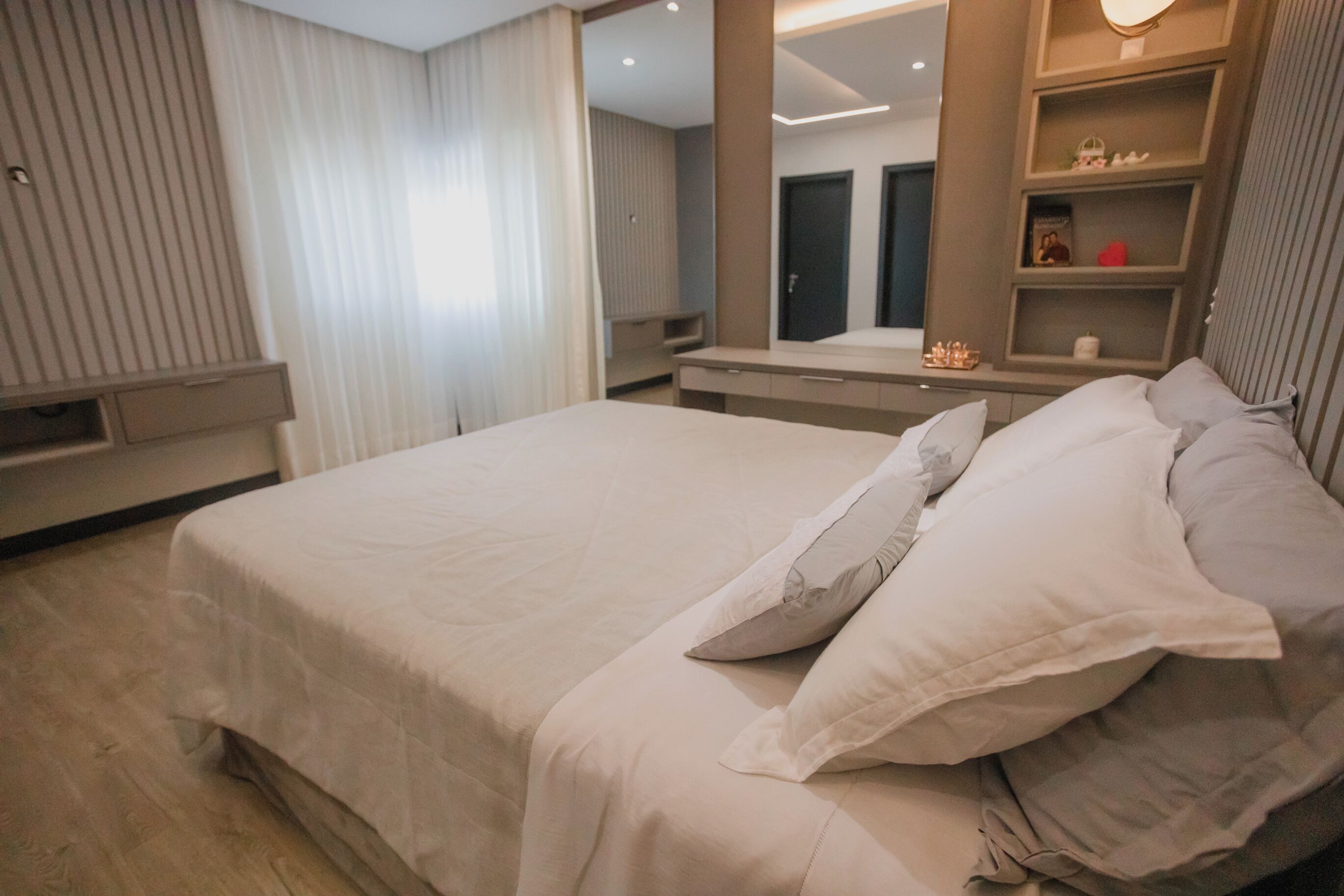 Habitación de hotel moderna con una cama grande, una mesita de noche, un espejo y una repisa con adornos.