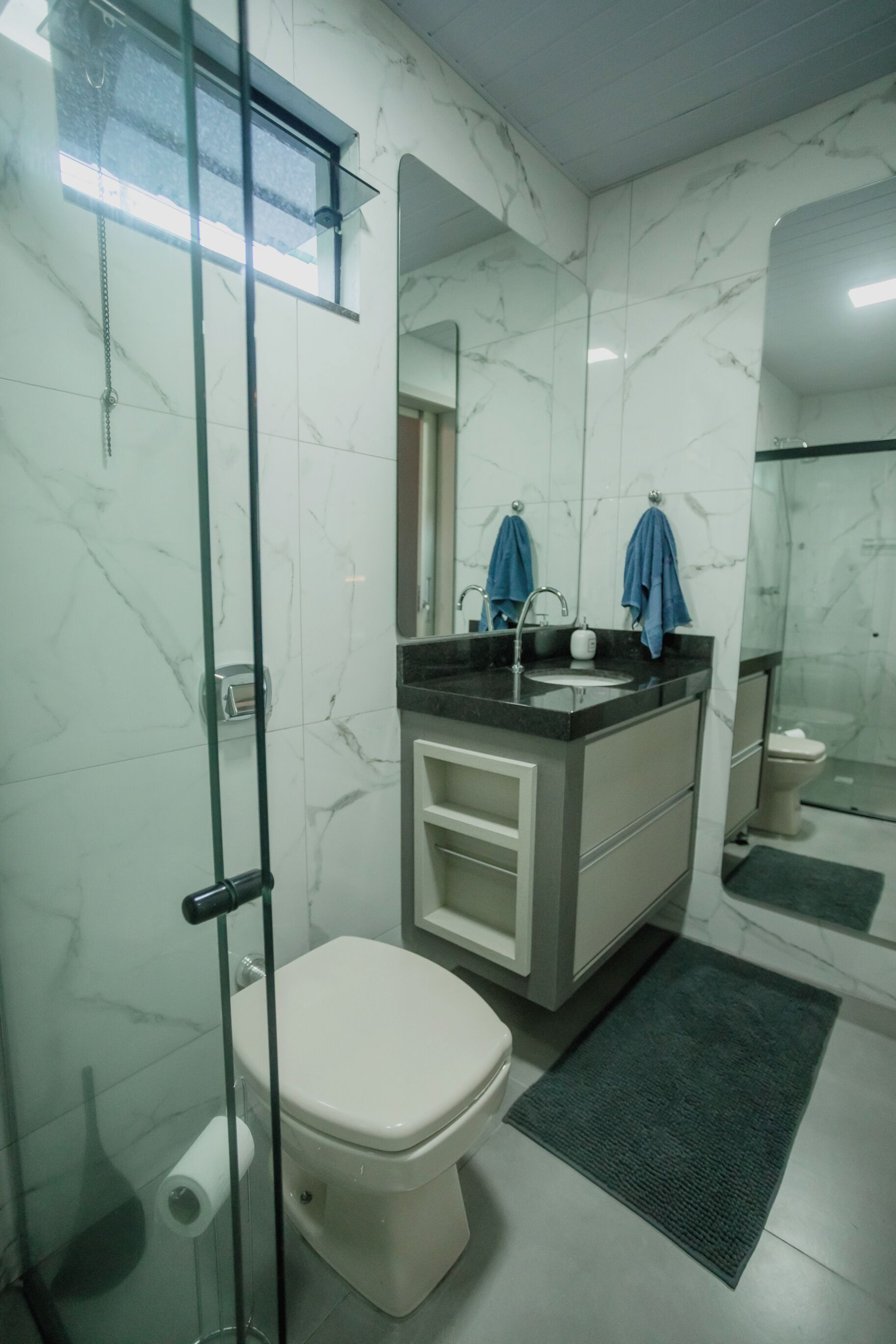 Un baño con inodoro, lavamanos, espejo y zona de ducha.
