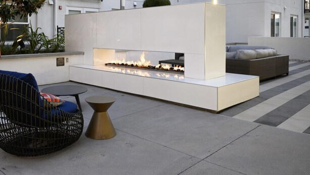A modern outdoor seating area with two wicker chairs, a round table, and a built-in fire feature. - Tangerine Terrace - 10 min to Disney/Angel Stadium (Orange)