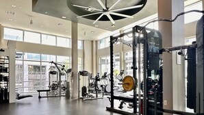 A spacious gym with various exercise equipment, large windows, and a high ceiling. - Casa Clementine - 10 min to SNA/Beach+Free Parking (Orange)