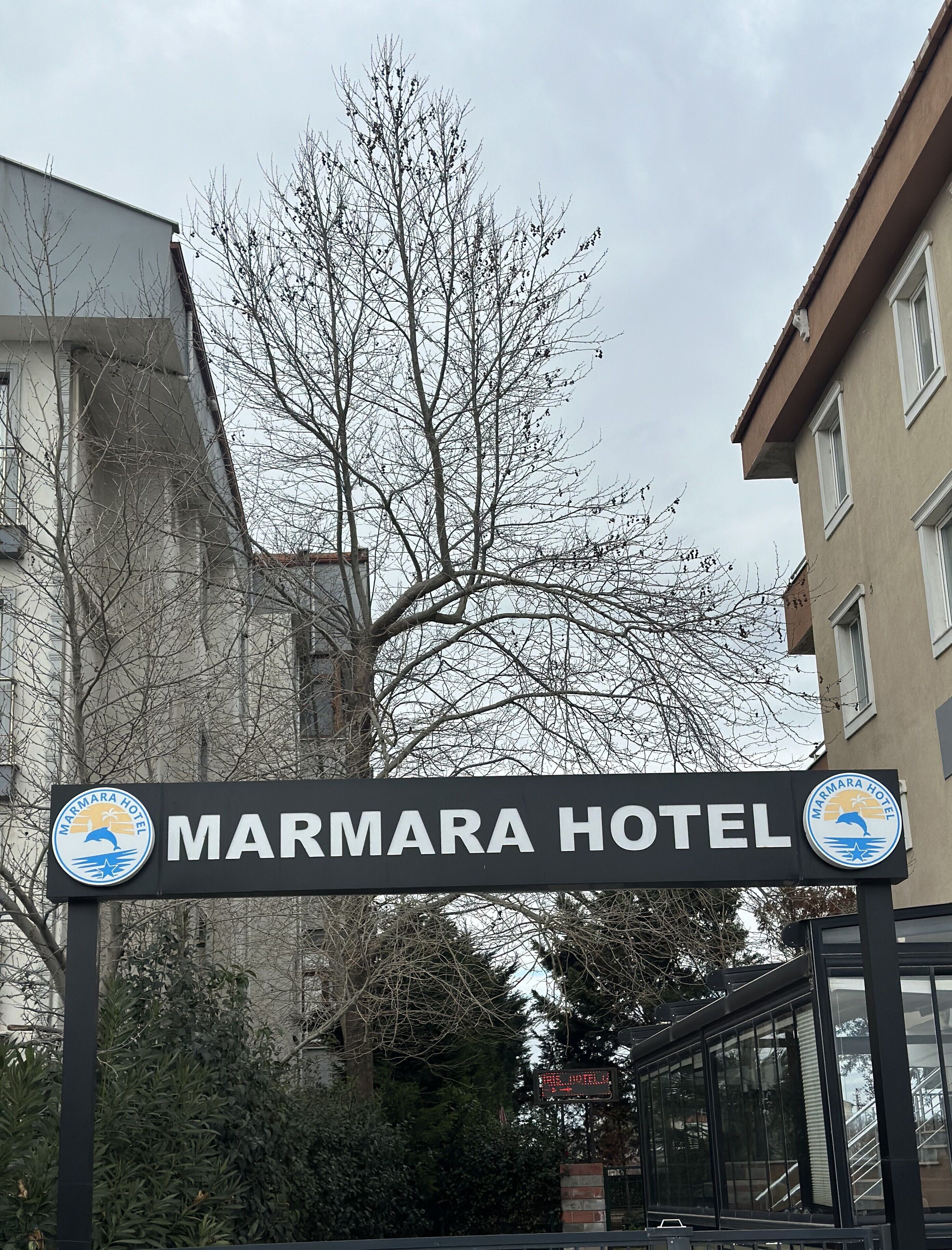 A sign for Marmara Hotel with a logo featuring a dolphin and sun.