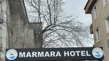 A sign for Marmara Hotel with a logo featuring a dolphin and sun.