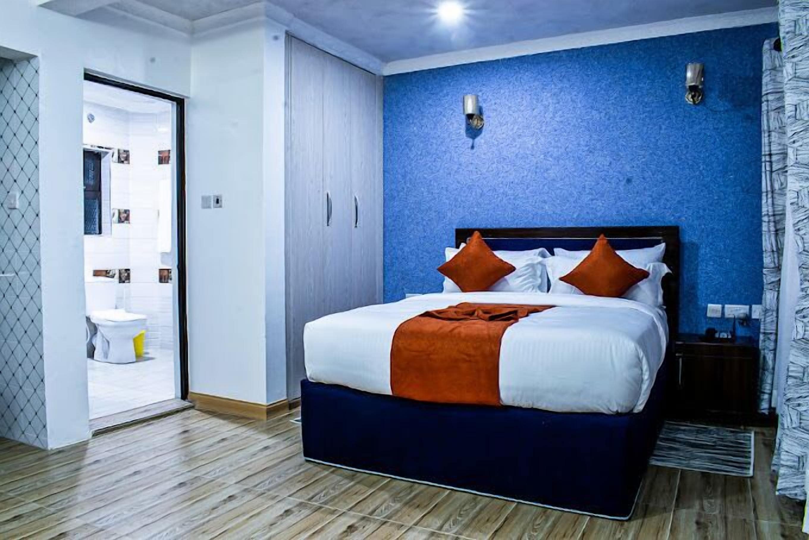 A bedroom with a bed, a wardrobe, and a bathroom visible through an open door.