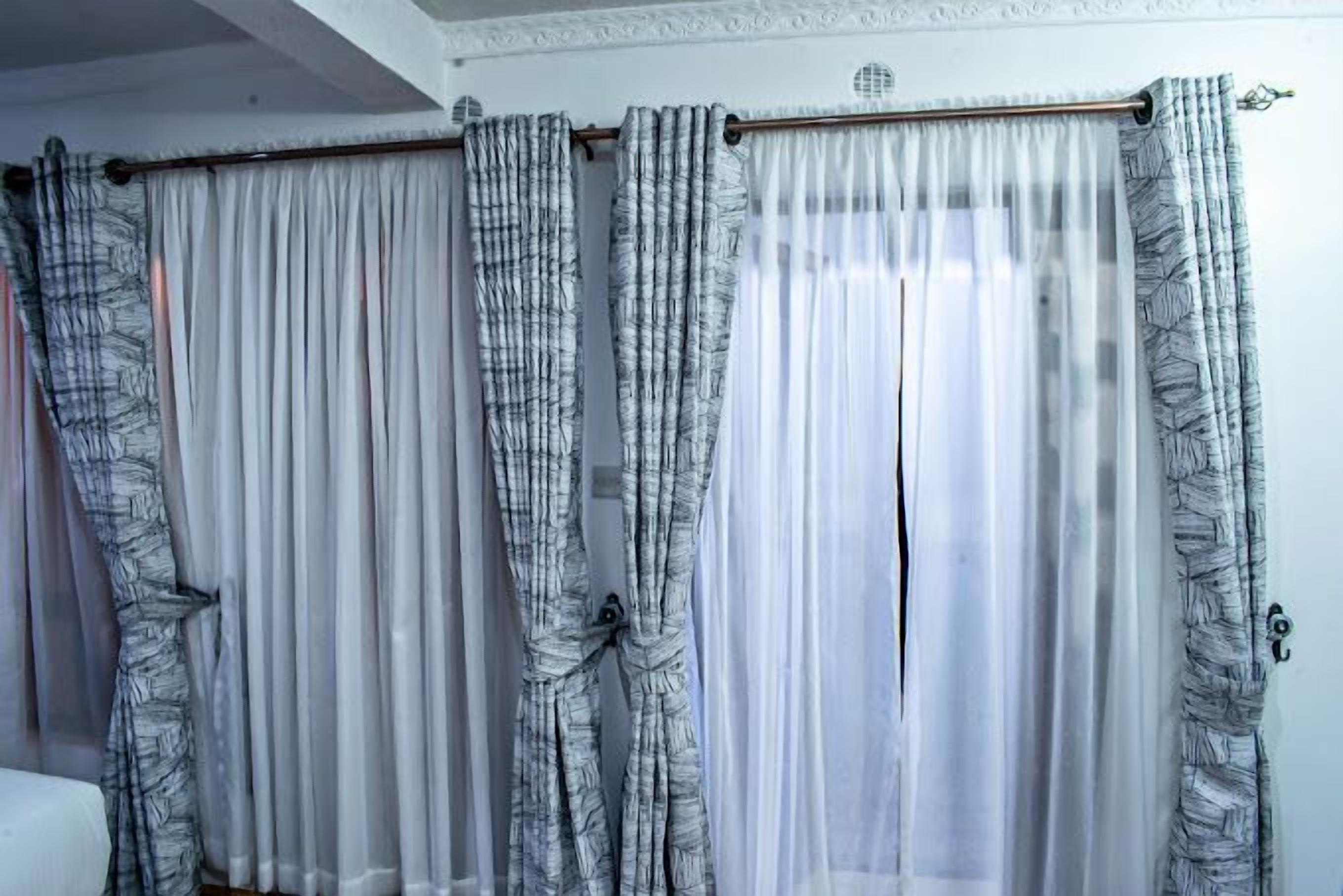 A room with a window covered by a curtain rod with multiple curtains.