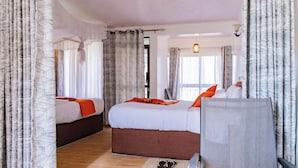A hotel room with two beds, a sitting area, and a view of the outdoors. - Wonderland Destinations Resort (Naivasha)