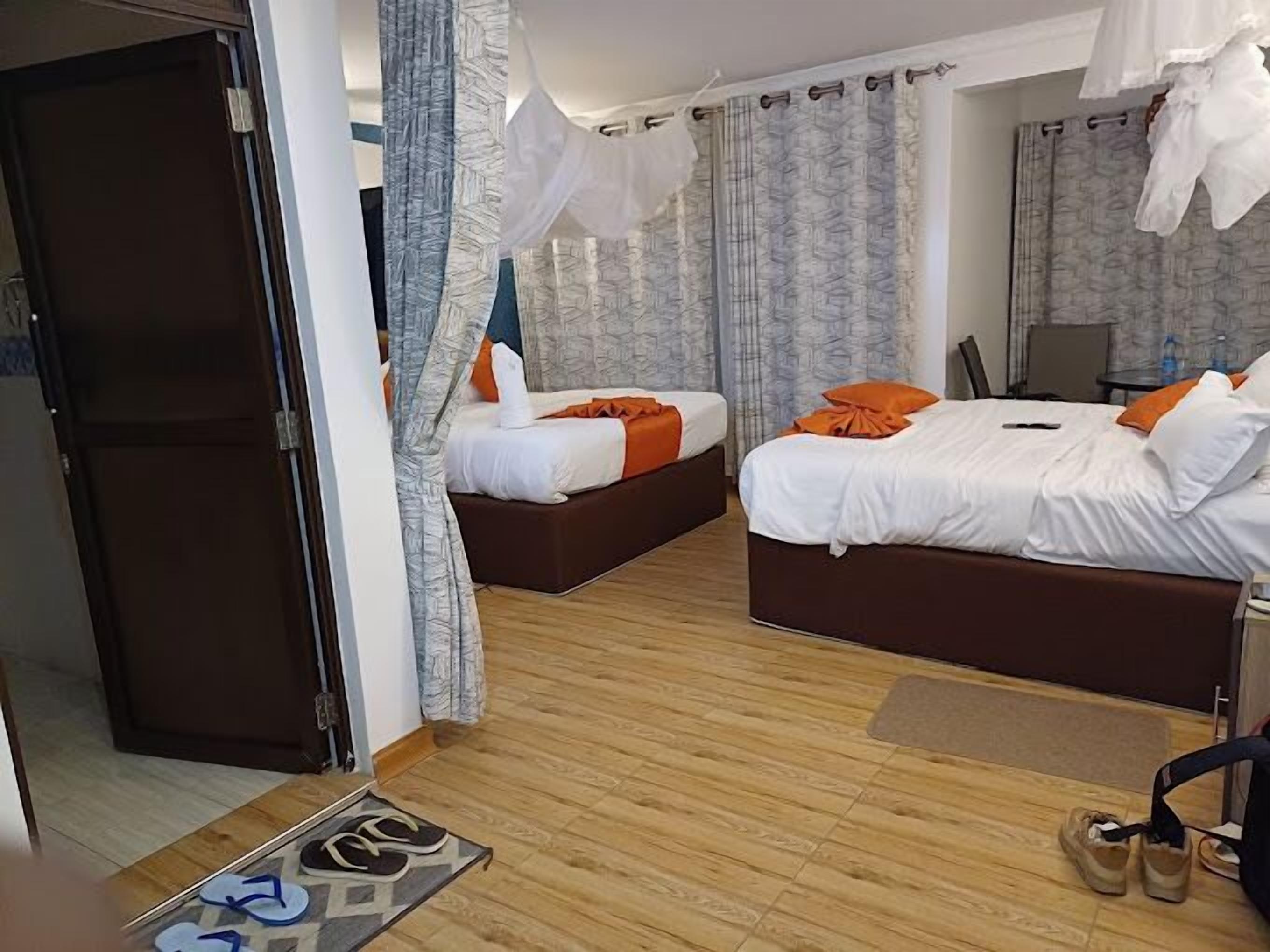Una habitación de hotel con dos camas, piso de madera y una puerta.