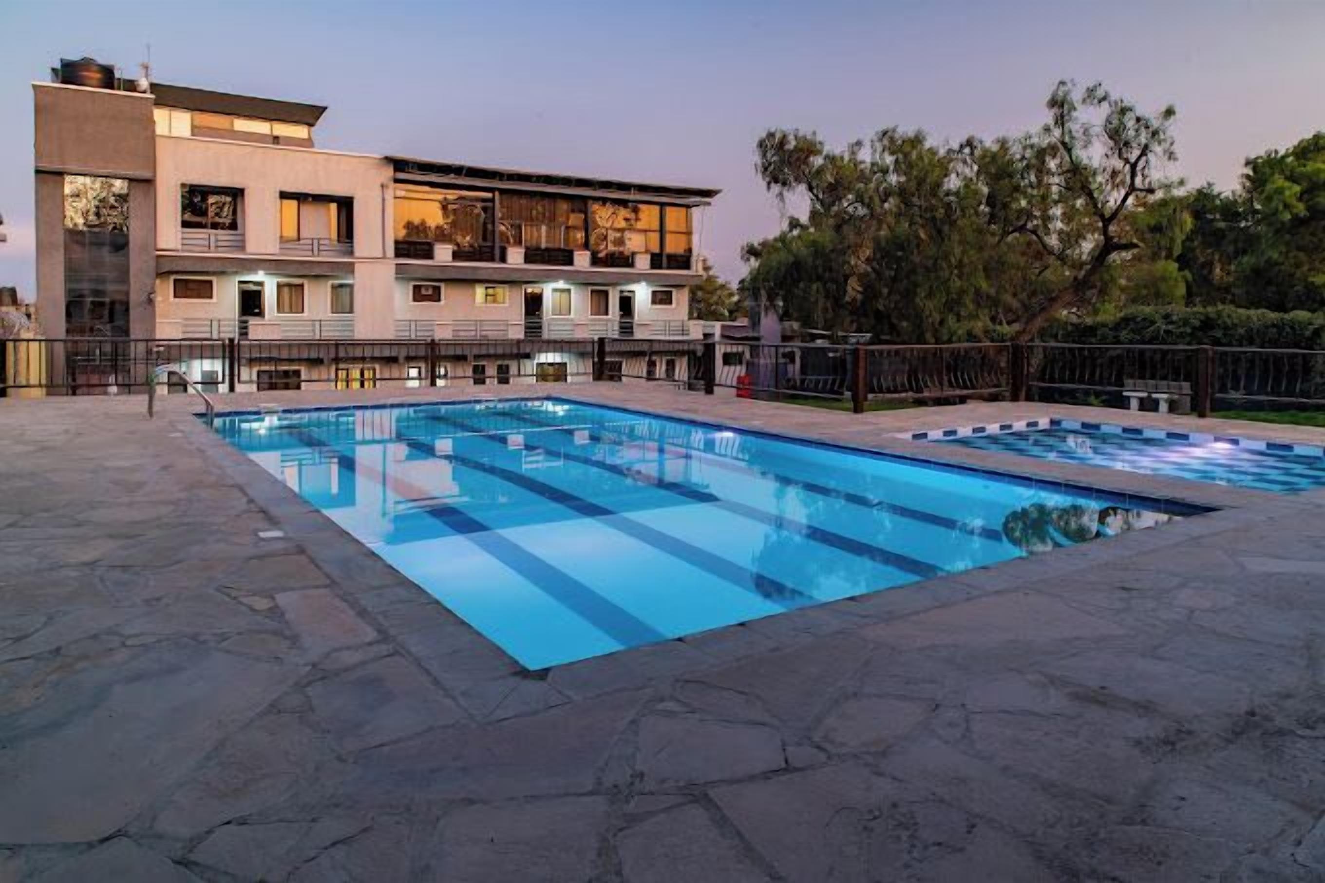 A modern building with a swimming pool and a stone patio.