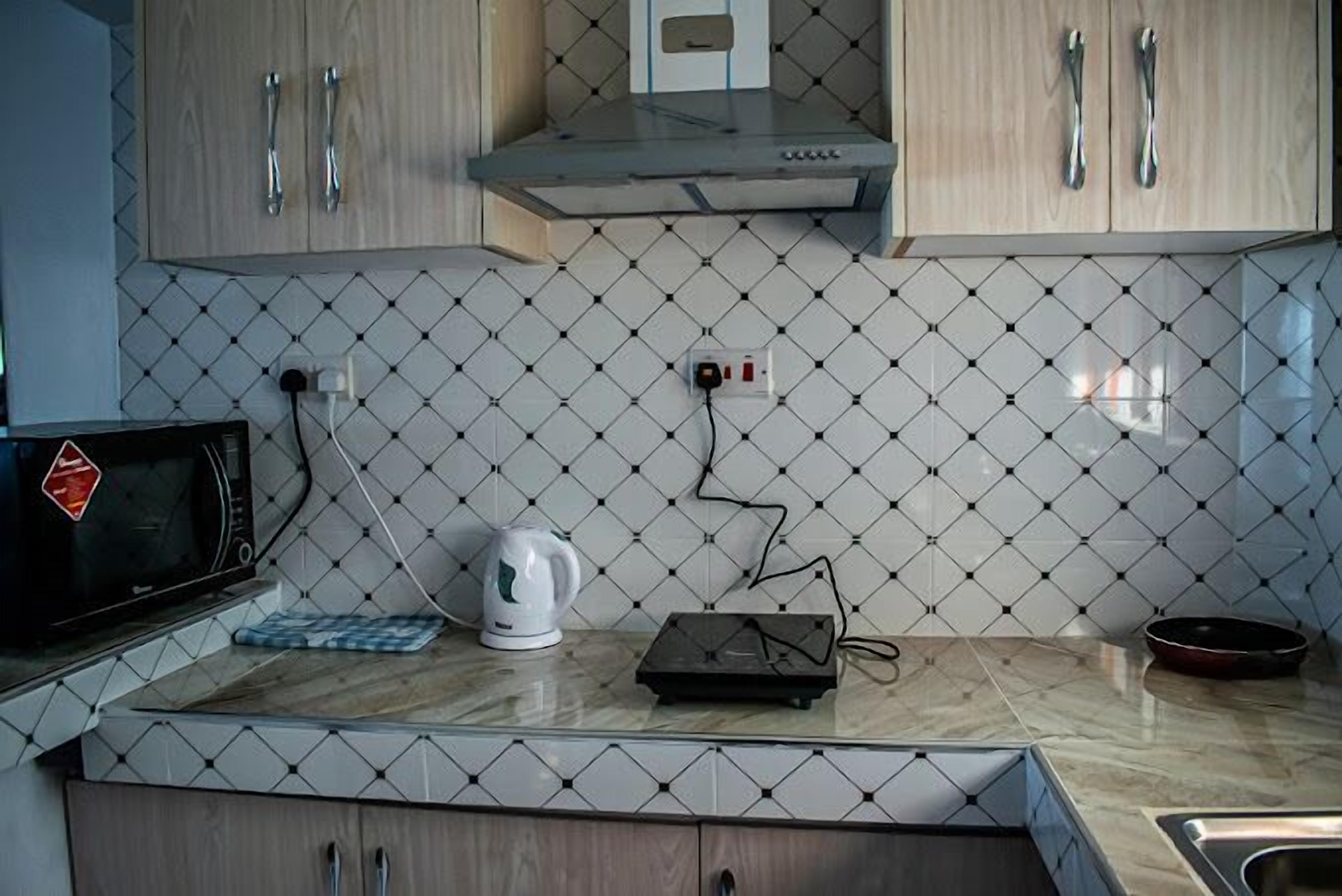 Una cocina con microondas, hervidor y un pequeño electrodoméstico en la encimera.