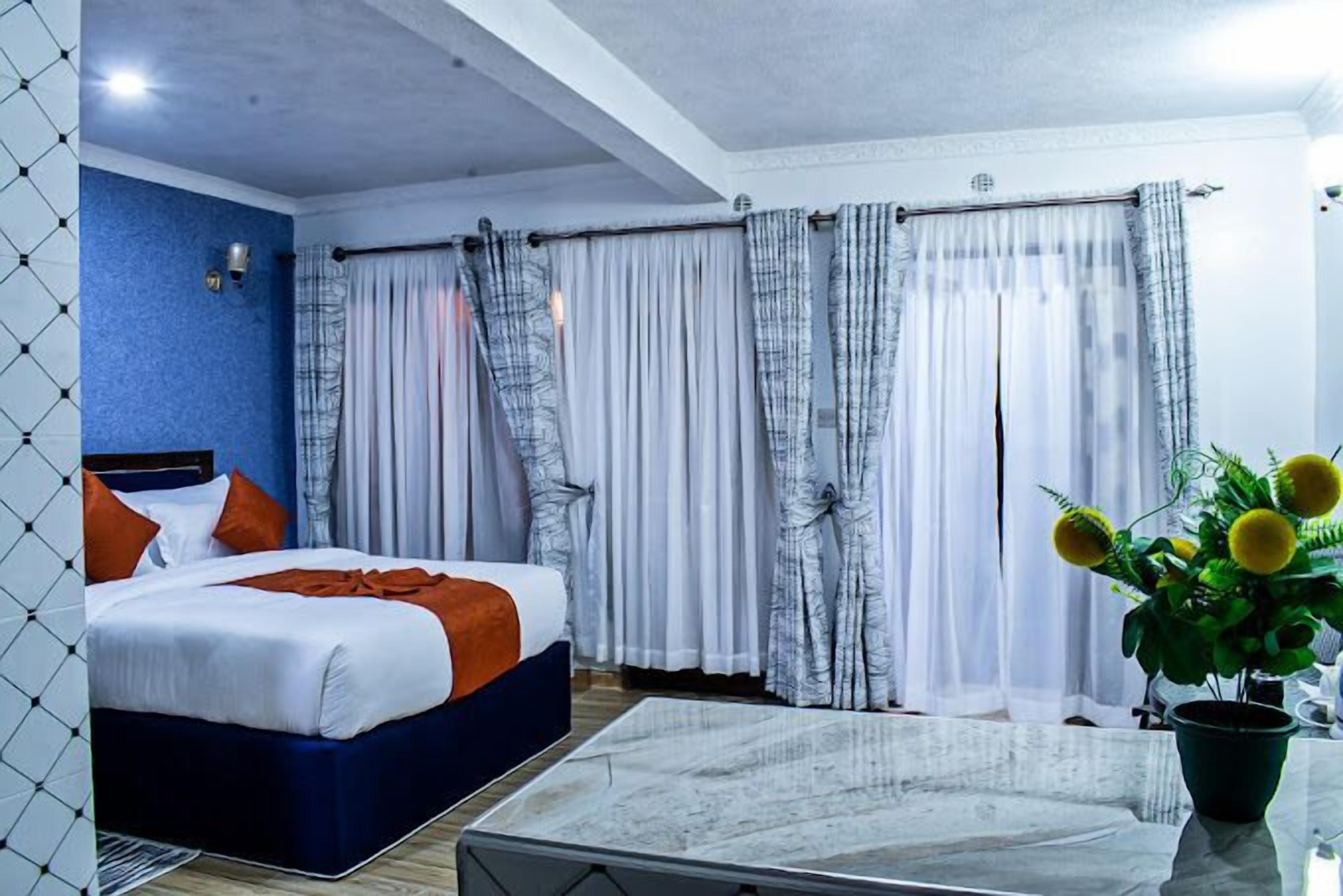 Una camera d'albergo con un letto, un tavolino da caffè e tende.