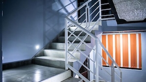 A staircase with white railings and a window with orange curtains. - Wonderland Destinations Resort (Naivasha)