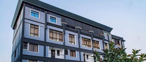 A multi-story building with a modern architectural design, featuring balconies and large windows.