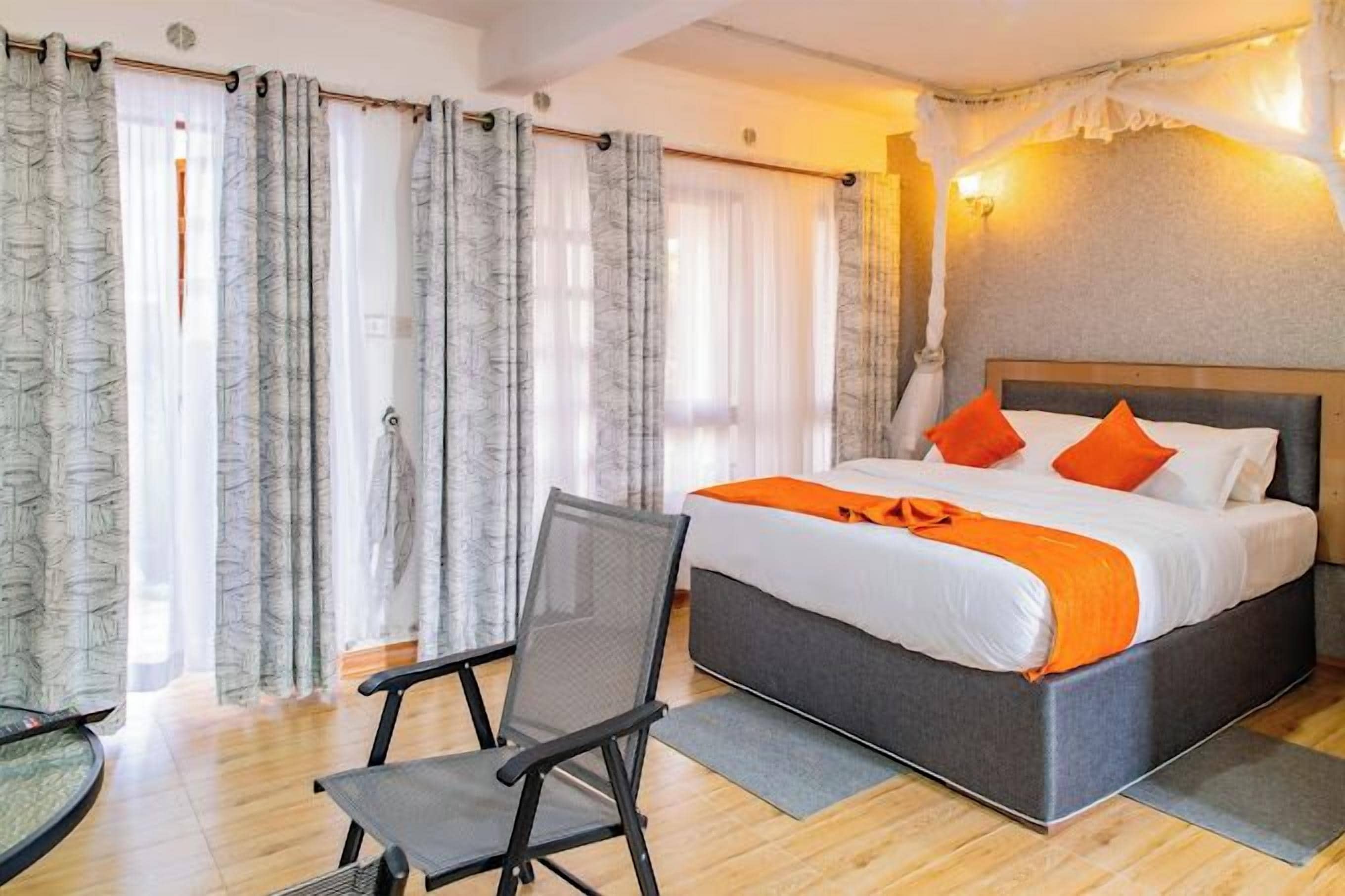 Un dormitorio con cama, una silla y cortinas.