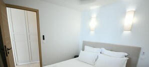 Ein Schlafzimmer mit einem Bett, einer Tür und zwei Wandleuchten.