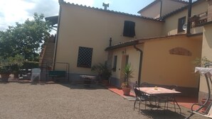 Un immeuble résidentiel doté d’un patio, d’une table avec des chaises et de plantes en pot.