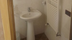 Une salle de bain avec un lavabo sur colonne, un porte-serviettes et un radiateur.