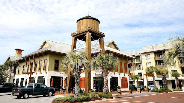 Un hotel con una torre central, varios balcones y palmeras.