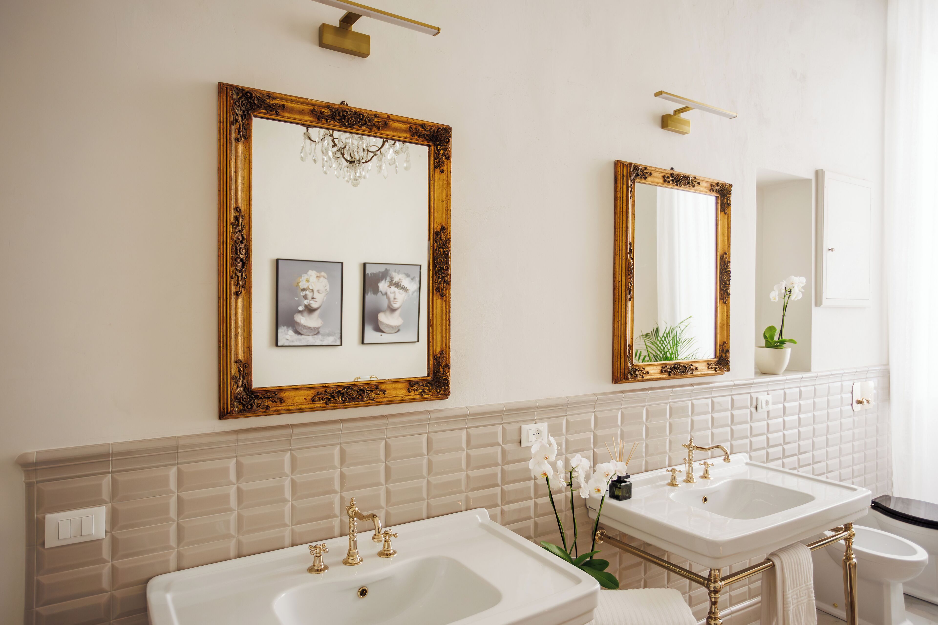 Un baño con dos lavamanos, un espejo y una araña.