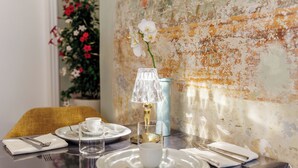 A dining table set with plates, cups, and cutlery, a clear glass, and a lamp. - PALAZZO DELLA BIANCA- Royal Experience (Pisa)
