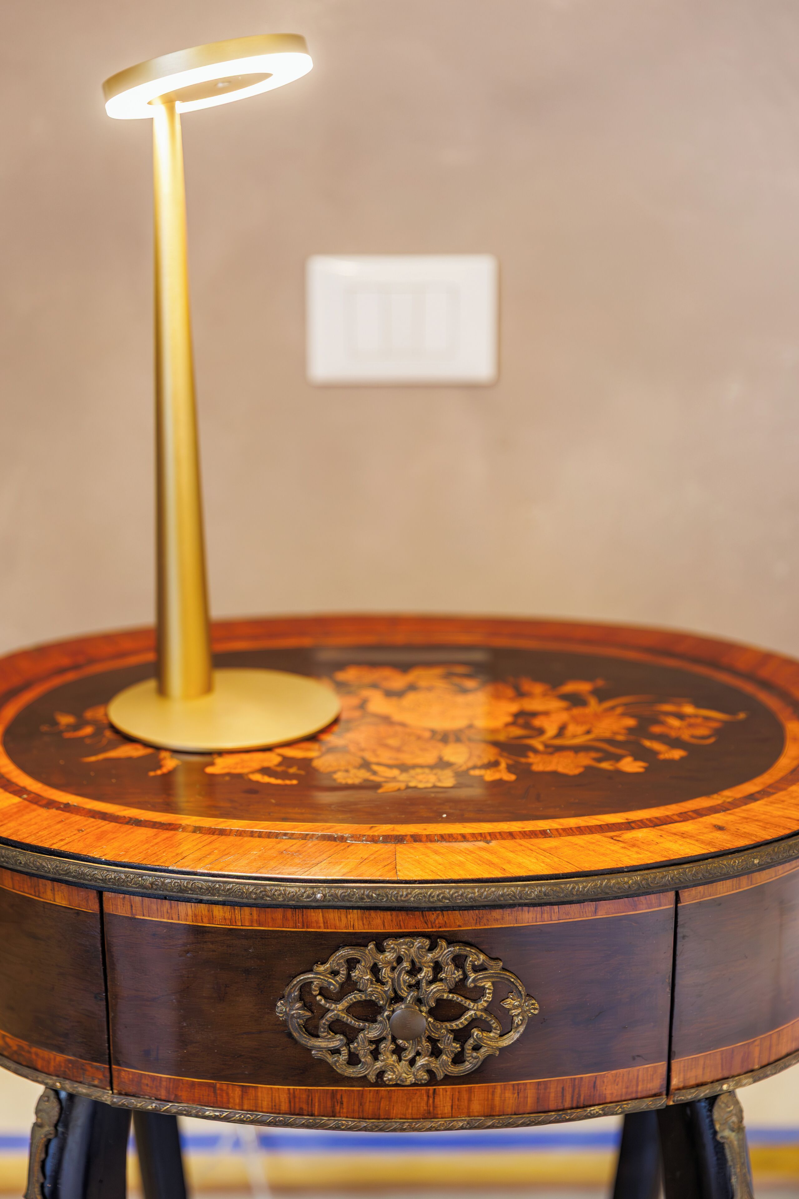 A round wooden table with a brass base and a lit lamp.
