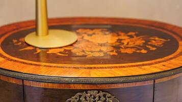 A round wooden table with a brass base and a lit lamp.