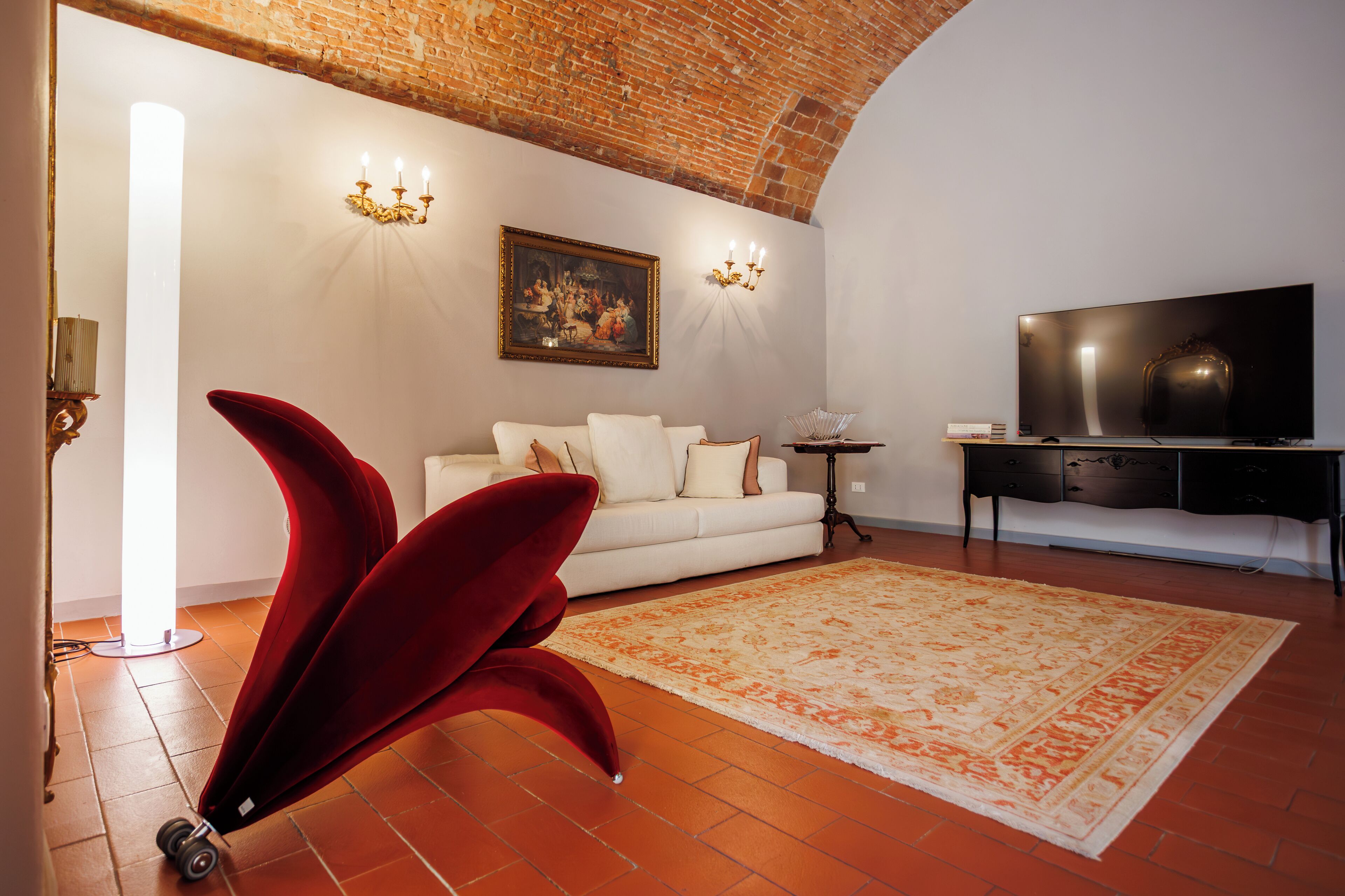 Una sala de estar con un sofá blanco, un sillón rojo y un tapete grande.