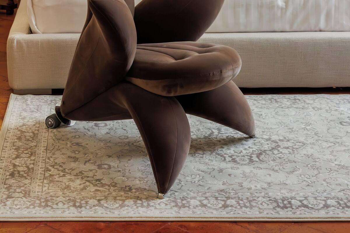 Une chambre à coucher avec un lit, deux oreillers jaunes, une œuvre d’art encadrée accrochée au mur et une chaise marron originale placée devant le lit.