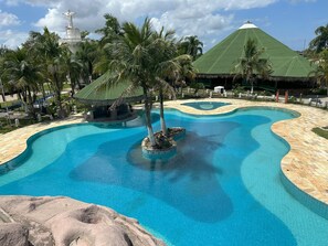 A swimming pool with a tropical theme, surrounded by palm trees and a thatched-roof structure. - Porto marina resort Ilha Comprida (Ilha Comprida)