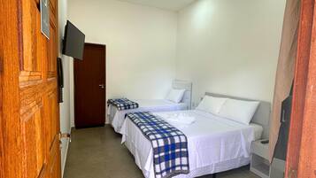 A hotel room with two beds, a TV mounted on the wall, and a wooden door.
