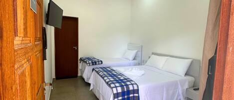 A hotel room with two beds, a TV mounted on the wall, and a wooden door.