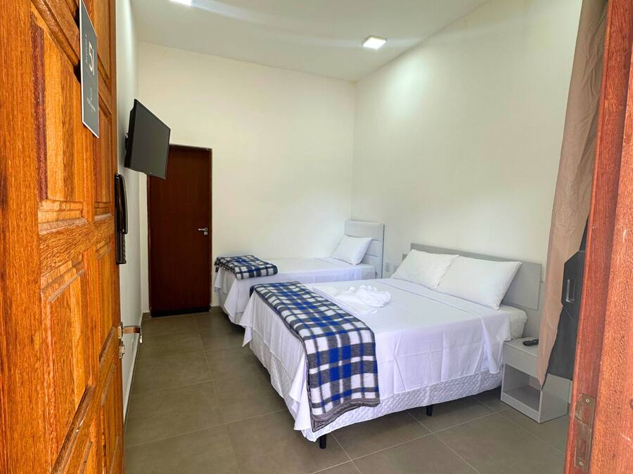 A hotel room with two beds, a TV mounted on the wall, and a wooden door.