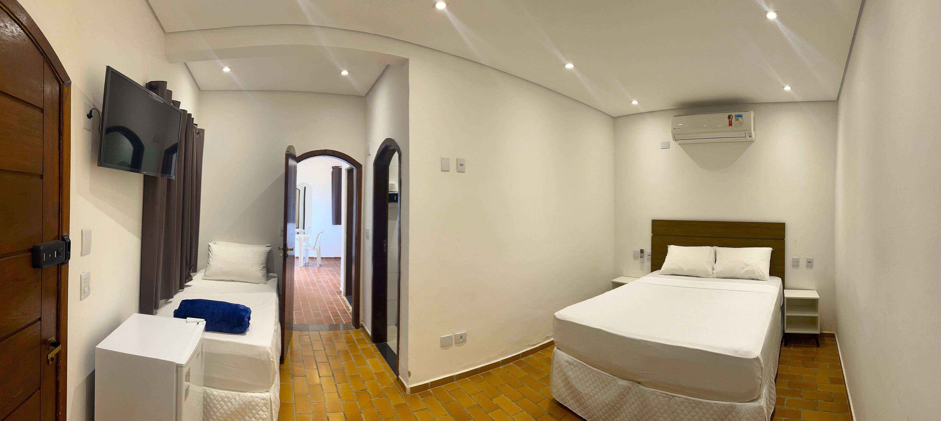 Ett hotellrum med en säng, en TV, en garderob och ett badrum.