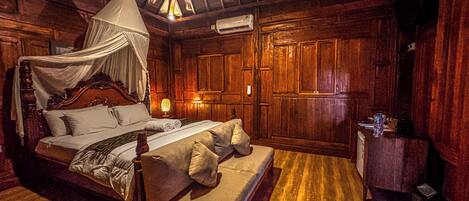 Een klassieke houten kamer met een hemelbed, een bank en een nachtkastje.