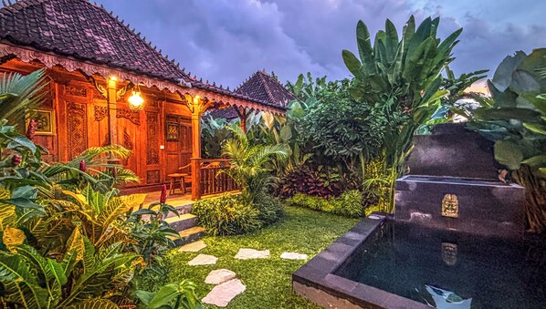 Una casa tradicional con techo de tejas, un porche de madera y una piscina pequeña.