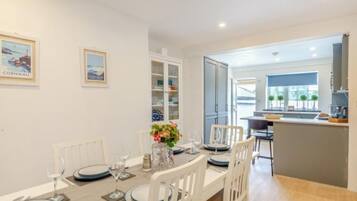 A dining area with a table set for four, white chairs, and a view into the kitchen.